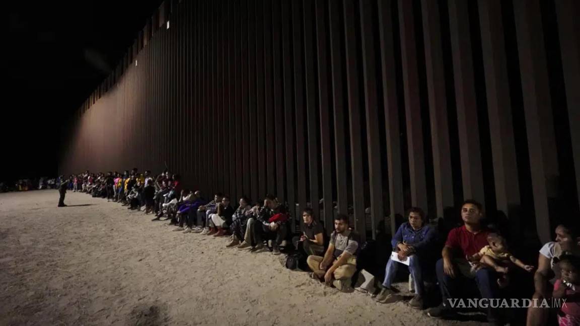 $!Migrantes esperan a lo largo de un muro fronterizo el 23 de agosto de 2022, después de cruzar desde México cerca de Yuma, Arizona.