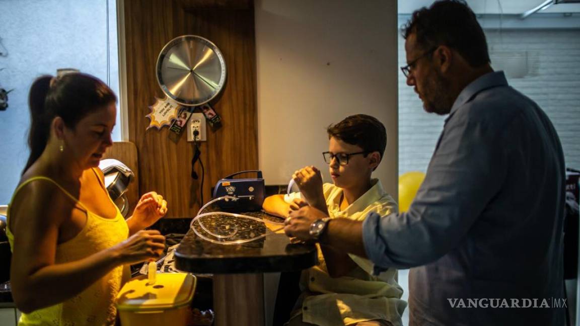 $!Rodrigo Rockenbach, de 11 años, que vive con fibrosis quística, usa un nebulizador mientras sus padres observan en Curitiba, Brasil.