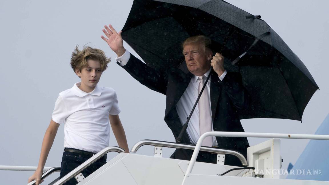 Donald Trump se cubre con un paraguas mientras se mojan su esposa y su hijo menor