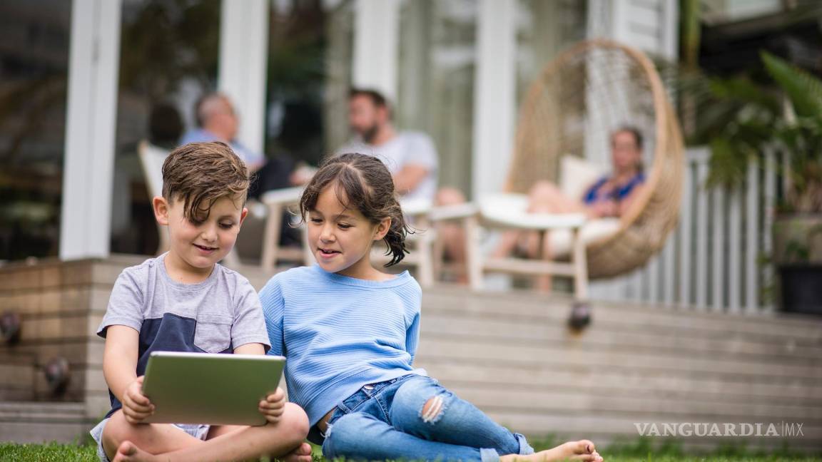 $!Niña y niño observando contenido digital en una 'tablet'.