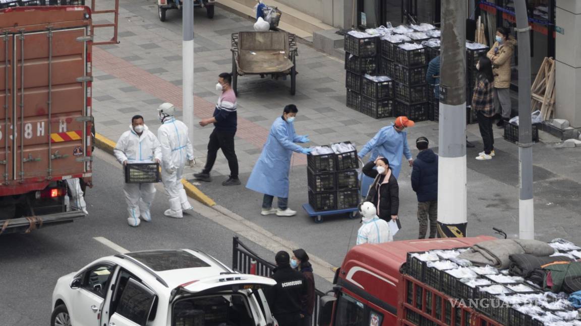 $!Trabajadores con equipo de protección personal descargan comestibles de un camión antes de distribuirlos a los residentes de Shanghái, China.