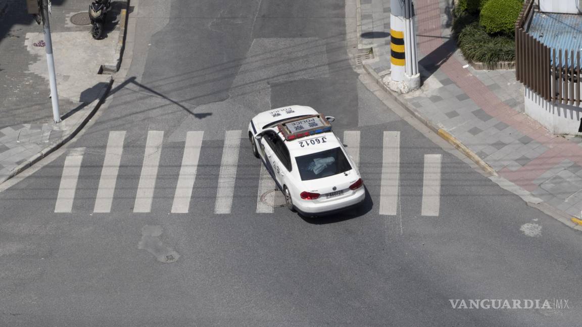 $!Un coche de policía patrulla una calle vacía en Shanghai, China.