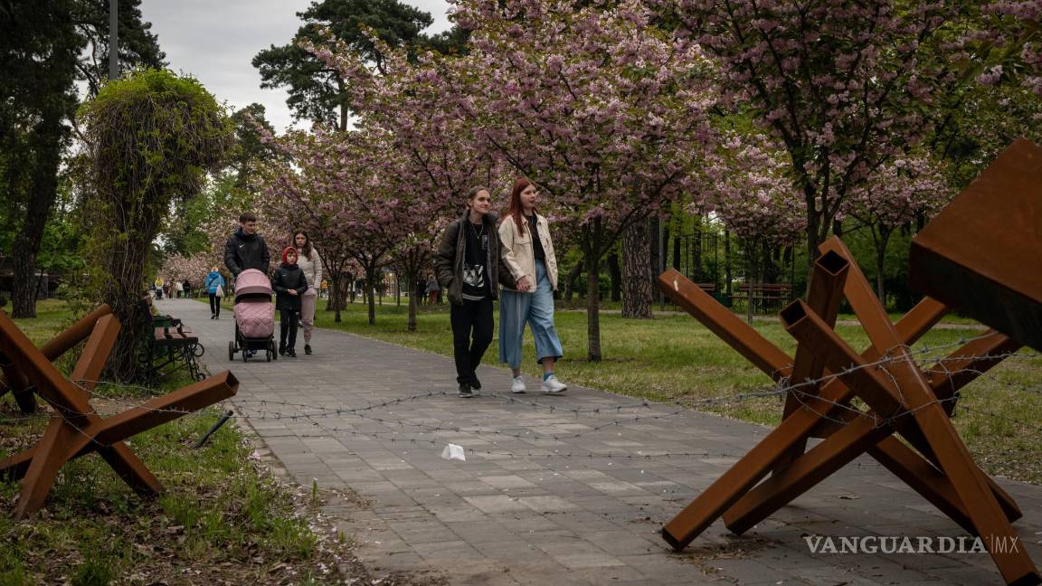 $!La gente camina por un camino bordeado de flores de cerezo y bloqueado por una barricada en un parque en Kiev, Ucrania