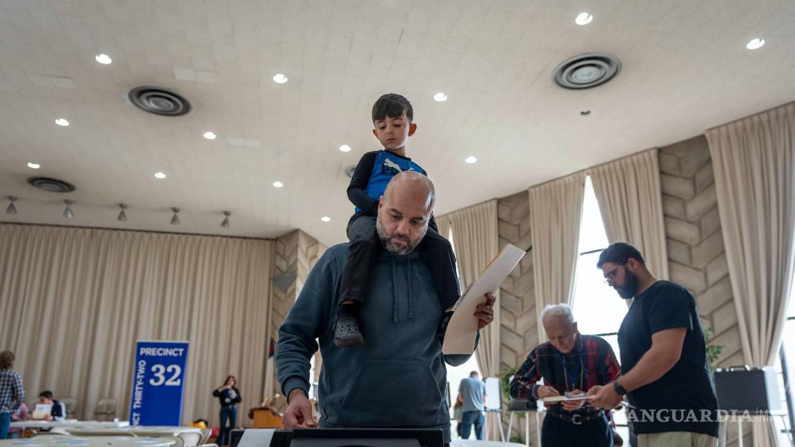 $!Three-year-old Zayn, sits on his father's shoulders as he inserts his ballot into a machine to vote at the First Presbyterian Church of Dearborn, on Election Day, Tuesday, Nov. 5, 2024, in Dearborn, Mich. (AP Photo/David Goldman)