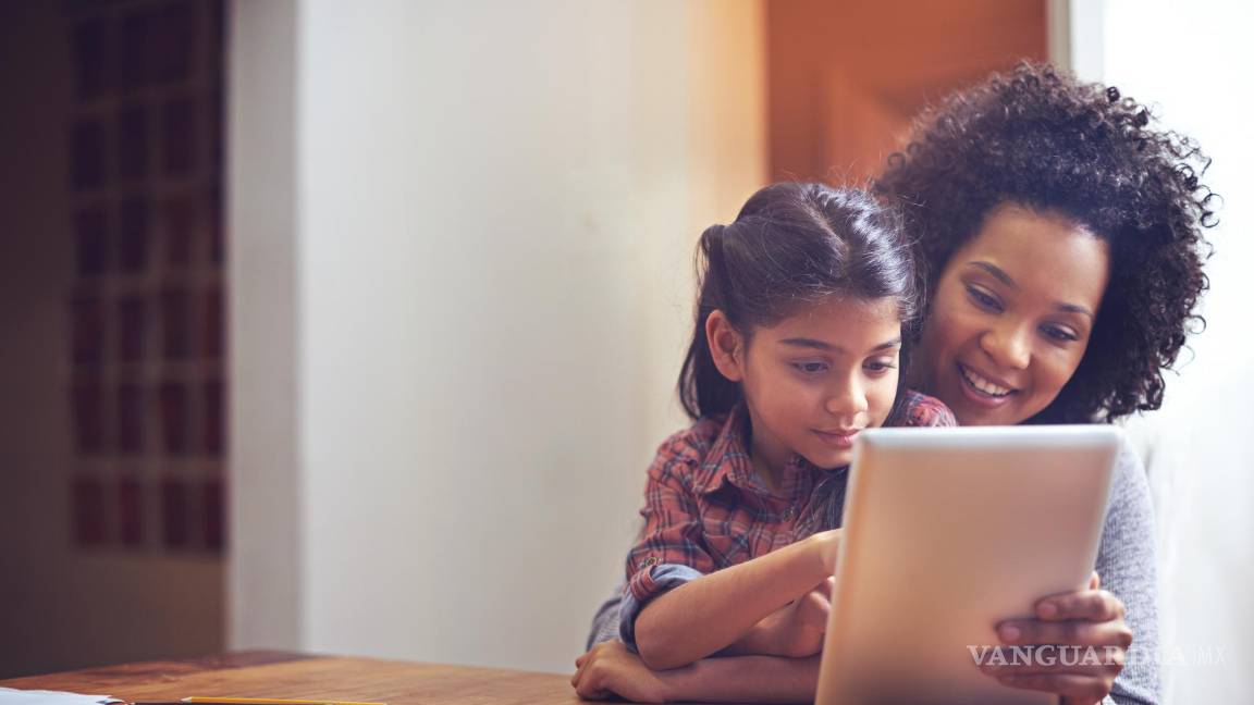 $!Madre e hija utilizando una tableta electrónica en el salón de su casa.
