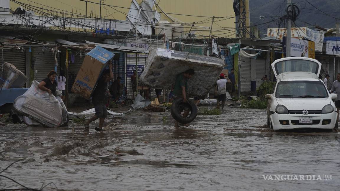 $!La gente camina con bienes saqueados de un centro comercial después de que el huracán Otis arrasara Acapulco, México.