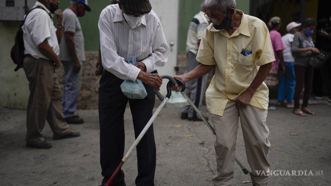 $!Hombres golpean sus bastones para despedirse después de recibir sus comidas donadas en un comedor de beneficencia en el barrio de La Vega de Caracas, Venezuela, el 11 de marzo de 2022.