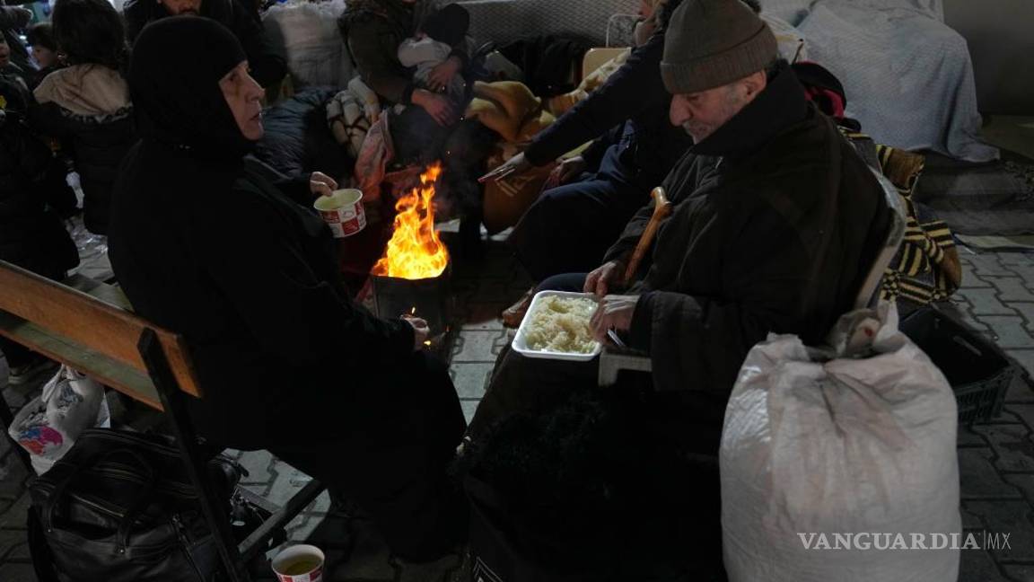 $!Varios sirios se calientan en torno al fuego en un refugio en Antakya, en el sureste de Turquía.