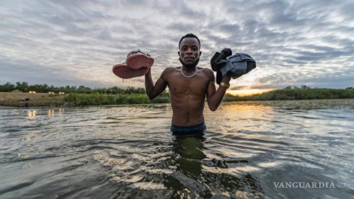 $!Migrante posa al amanecer sujetando sus pertenencias en la línea fronteriza que cruza el río. Foto: Omar Saucedo