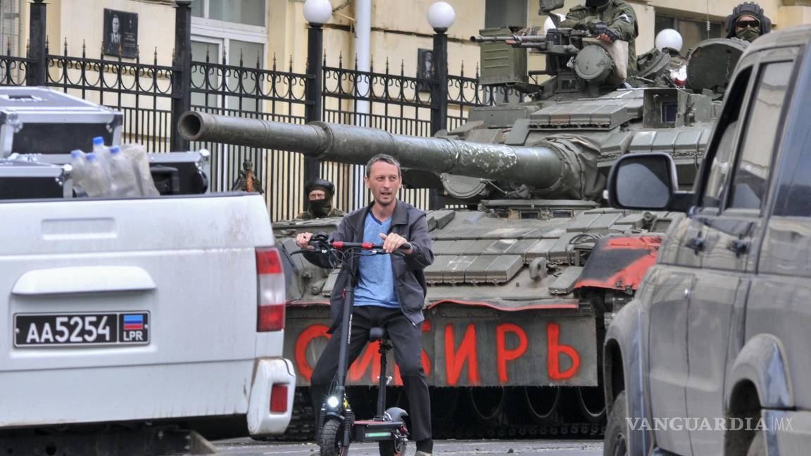 $!Un hombre monta un scooter junto a los militares de la compañía militar privada (PMC) Wagner Group en un tanque que dice ‘Siberia’ en Rostov-on-Don, Rusia.