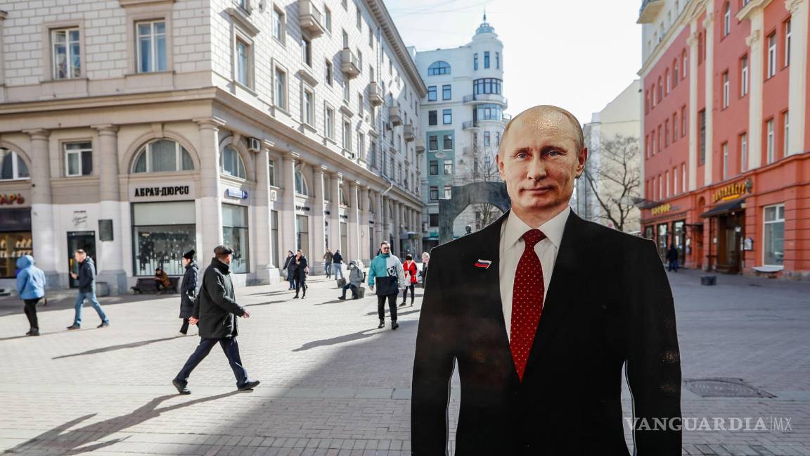 $!La gente pasa junto a una figura de cartón del presidente ruso y candidato presidencial Vladimir Putin en la calle de Moscú, Rusia.
