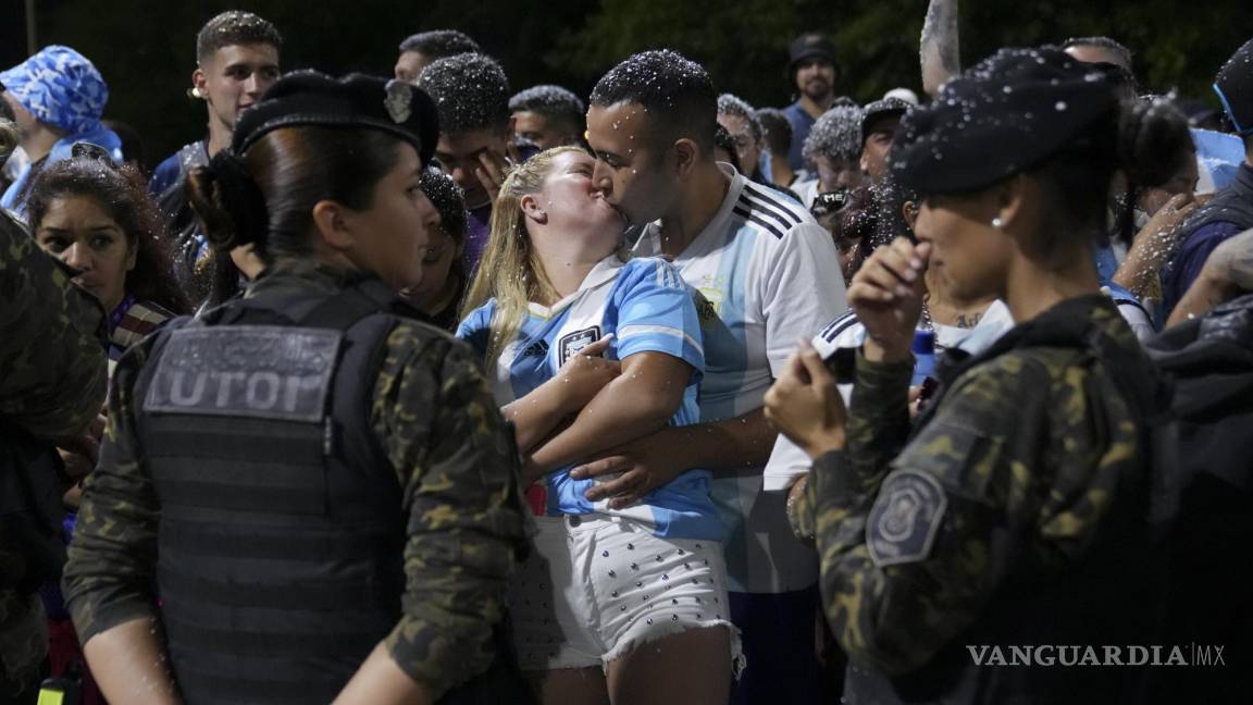$!Una pareja se besan mientras esperan la llegada de la selección argentina de fútbol que ganó la Copa del Mundo fuera del campo de entrenamiento de la AFA.