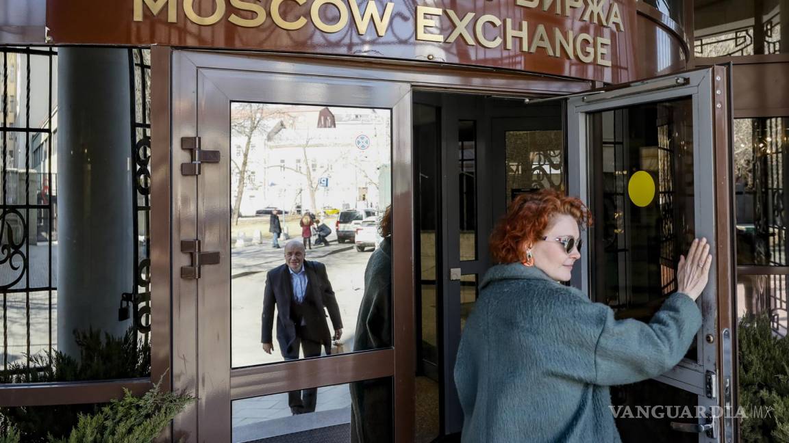 $!Una mujer entra en un edificio con un tablero con el logo de la Bolsa de Moscú en el centro de Moscú, Rusia.