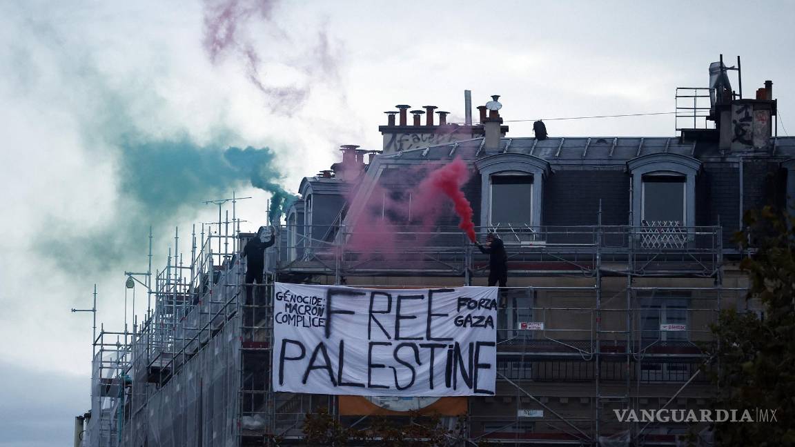 $!Dos manifestantes queman velas de humo en lo alto de un edificio junto a una pancarta de “Palestina libre”, para apoyar al pueblo palestino, en París, Francia.