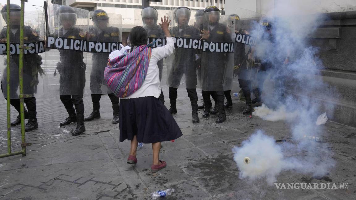 $!Una mujer intenta hacer retroceder a la policía con una oración y una Biblia durante los enfrentamientos en Lima, Perú.