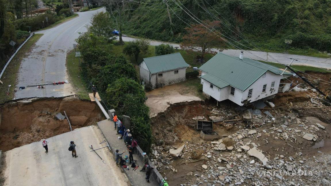$!La gente se reúne en un puente dañado sobre el río Broad en la autopista 64 en la comunidad Bat Cave de Carolina del Norte.
