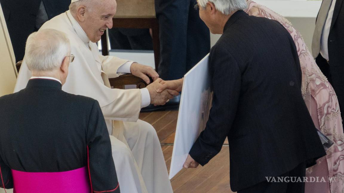 $!El fotógrafo ganador del premio Pulitzer, Nick Ut (c) y la embajador ade la UNESCO, Kim Phuc (d) le muestran al Papa Francisco la foto ganadora del Pulitzer de 1973.