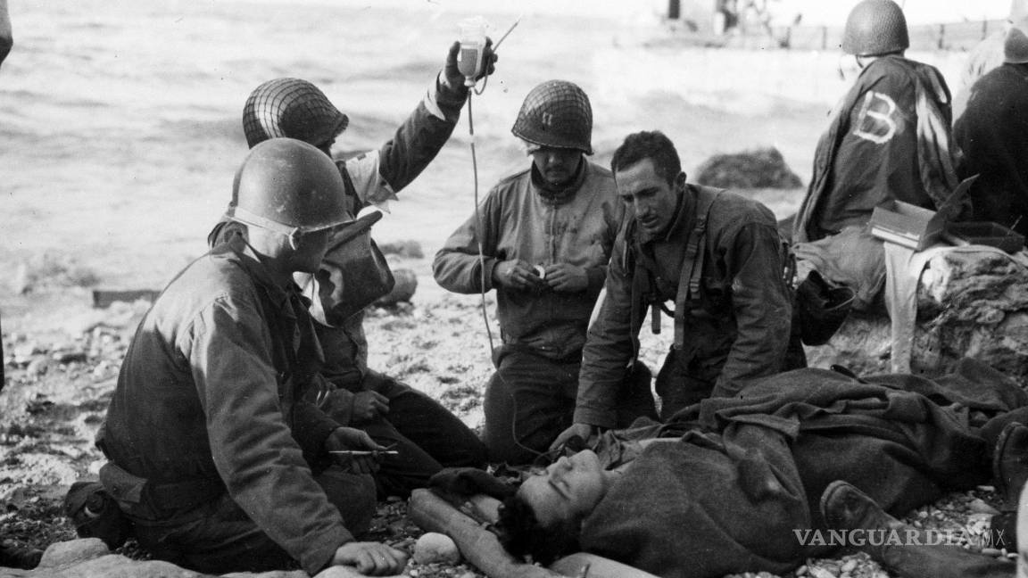 $!El personal médico del ejército estadounidense administra una transfusión de plasma a un soldado herido frente a la costa de Normandía, Francia.