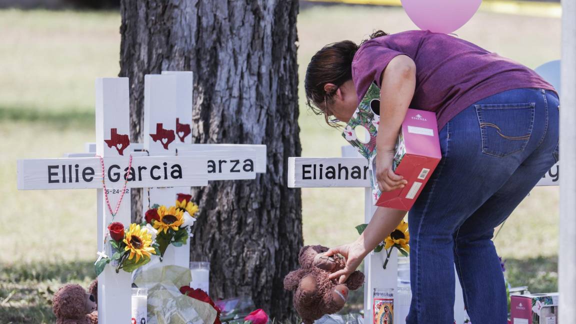$!Una mujer coloca un animal de peluche junto a una cruz con el nombre de una víctima después de un tiroteo en la Escuela Primaria Robb en Uvalde, Texas.