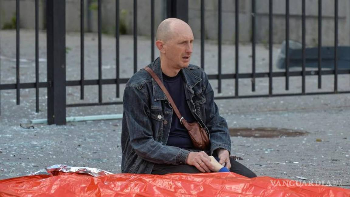 Padre ucraniano conmocionado sostiene la mano de su hijo de 13 años, muerto en un ataque ruso