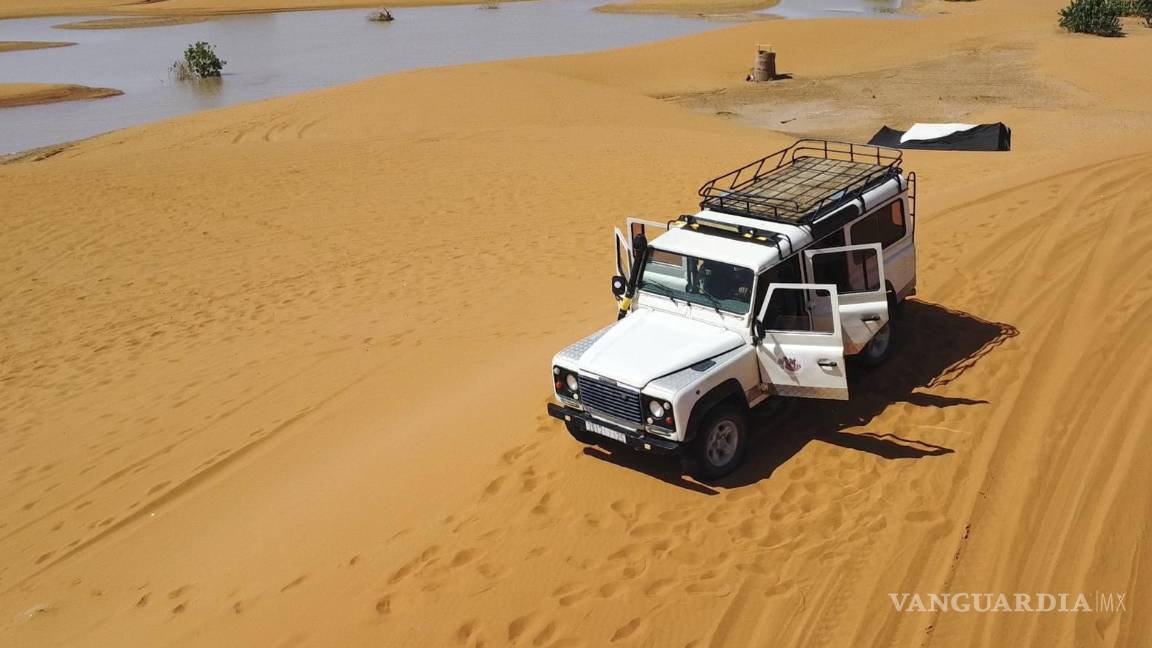 $!Un vehículo transporta turistas por las dunas de arena junto a un lago provocado por las fuertes lluvias en la ciudad desértica de Merzouga, cerca de Rachidia.
