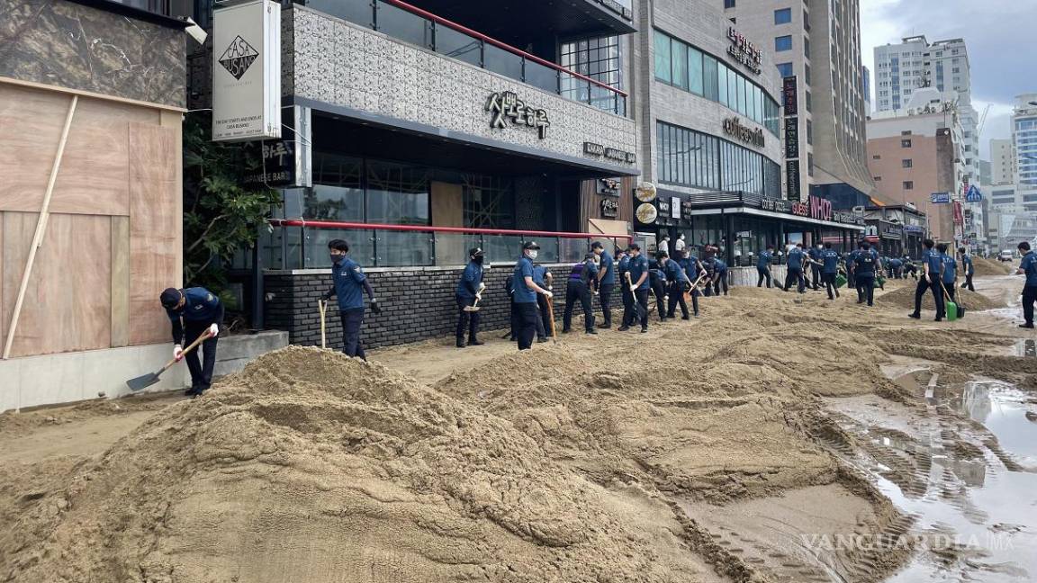$!Agentes de policía retiran montones de arena arrastrados a una carretera desde la playa de Gwangalli en Busan, Kore del Sur.