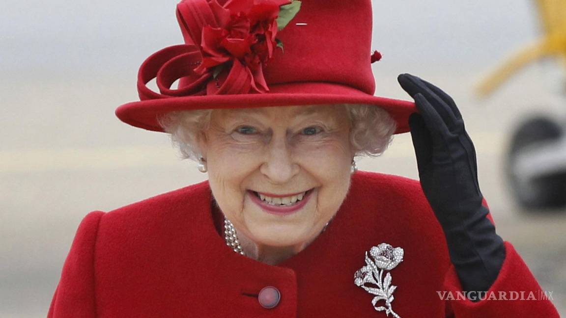 $!La reina Isabel II de Gran Bretaña sostiene su sombrero por los fuertes vientos al llegar a una visita al Valle RAF en Anglesey, Gales, el 1 de abril de 2011.