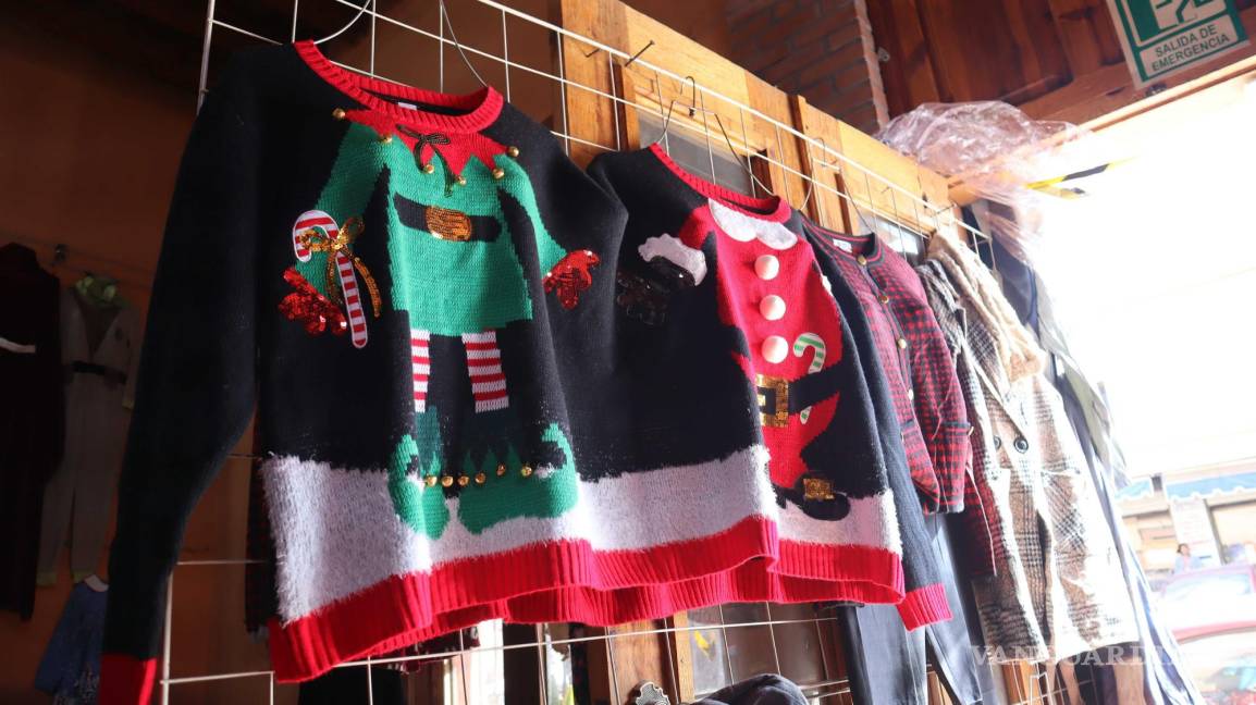 $!Coloridos suéteres con motivos navideños cuelgan en un tendedero, listos para ser adquiridos durante la temporada festiva en la ciudad.