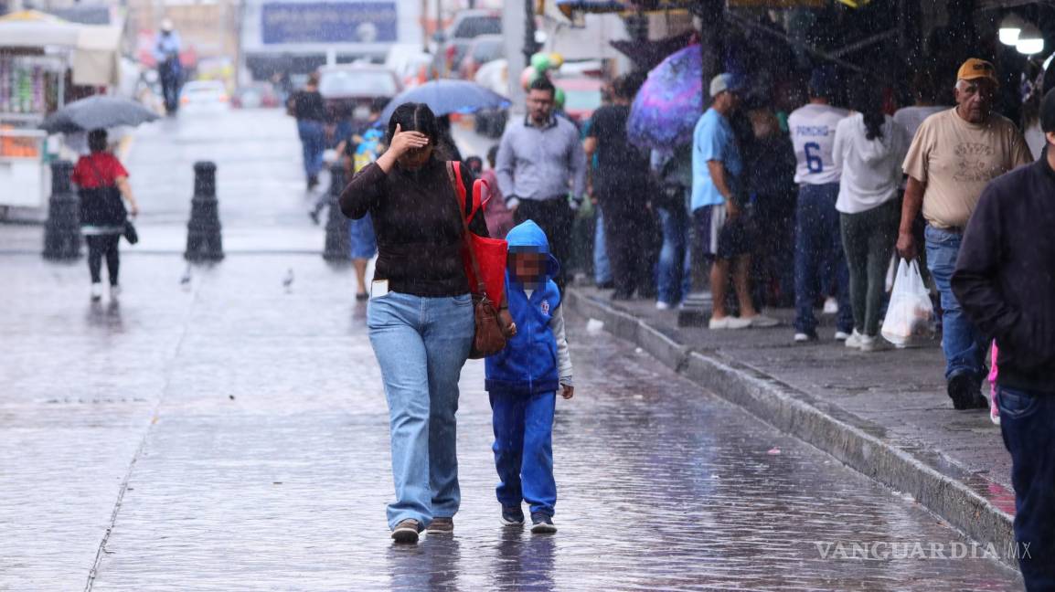 $!Residentes caminando bajo la lluvia, enfrentando las inclemencias del tiempo.