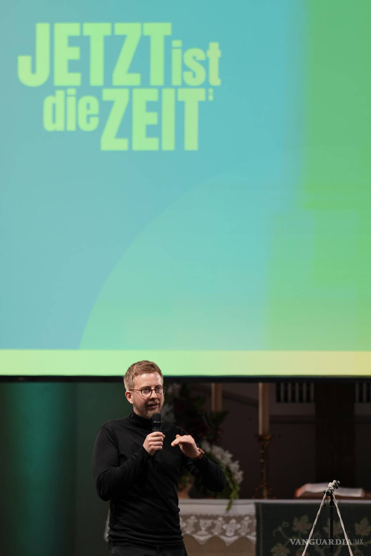 $!Jonas Simmerlein, teólogo y filósofo de la Universidad de Viena en Austria, frente a un eslogan que dice “El momento es ahora” en Nuremberg, Alemania.