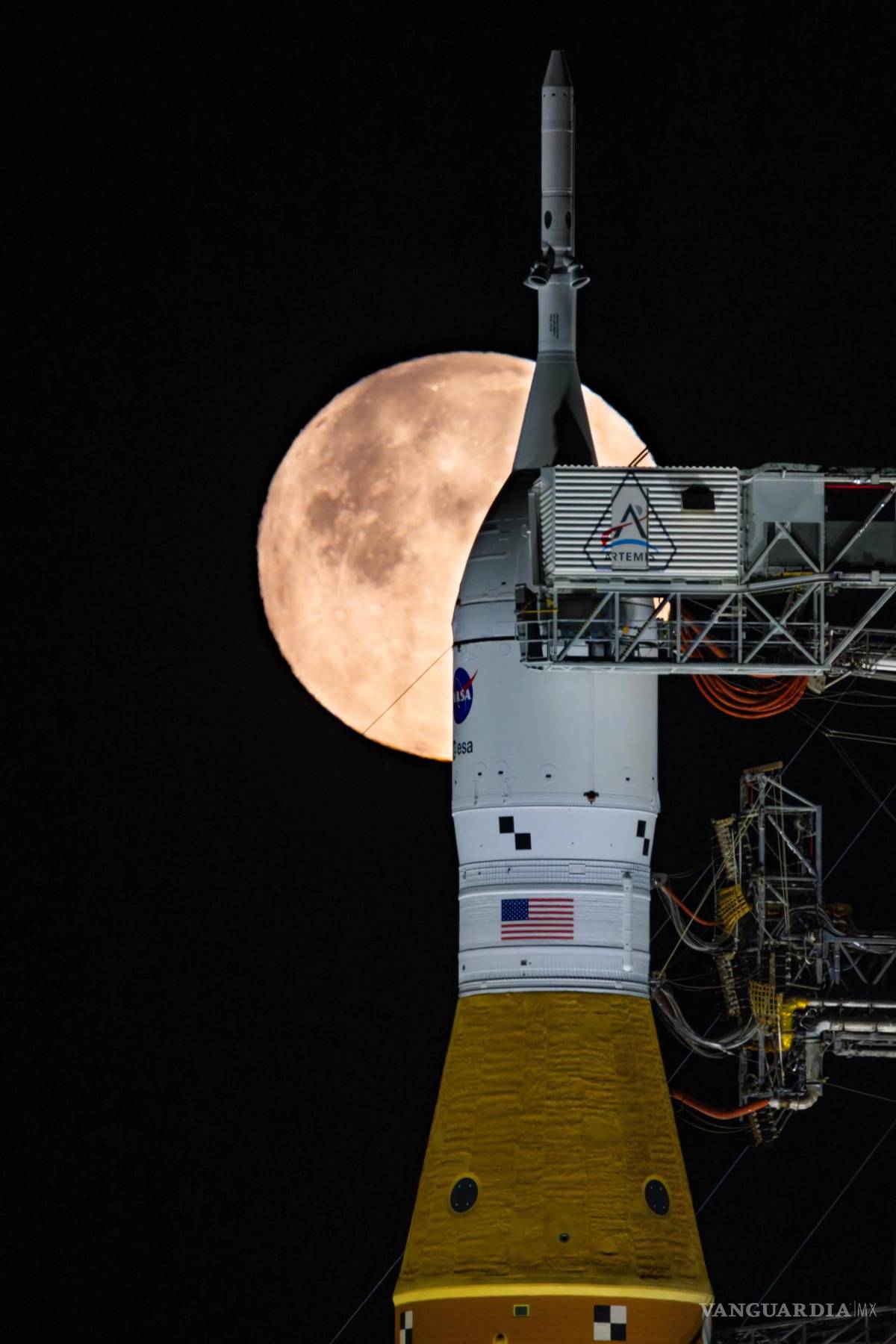 $!Una luna llena brillando detrás del cohete SLS y la nave espacial Orion sobre el lanzador móvil en el Centro Espacial Kennedy de la NASA, en Florida,