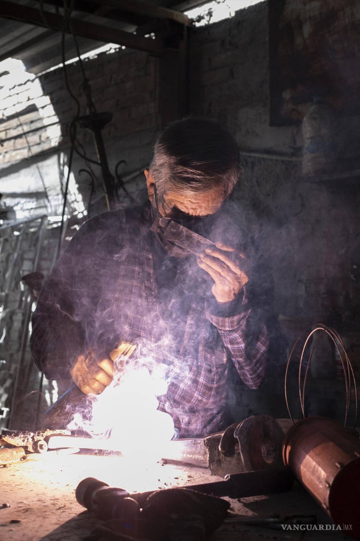 $!Con la izquierda sostiene una placa negra para proteger sus ojos, con la derecha crea chispas en el metal.