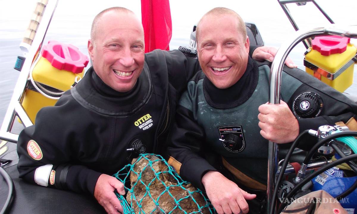$!Julian y Lincoln Barnwell posan para una foto con la campana del HMS Gloucester, encontrada en 2007.