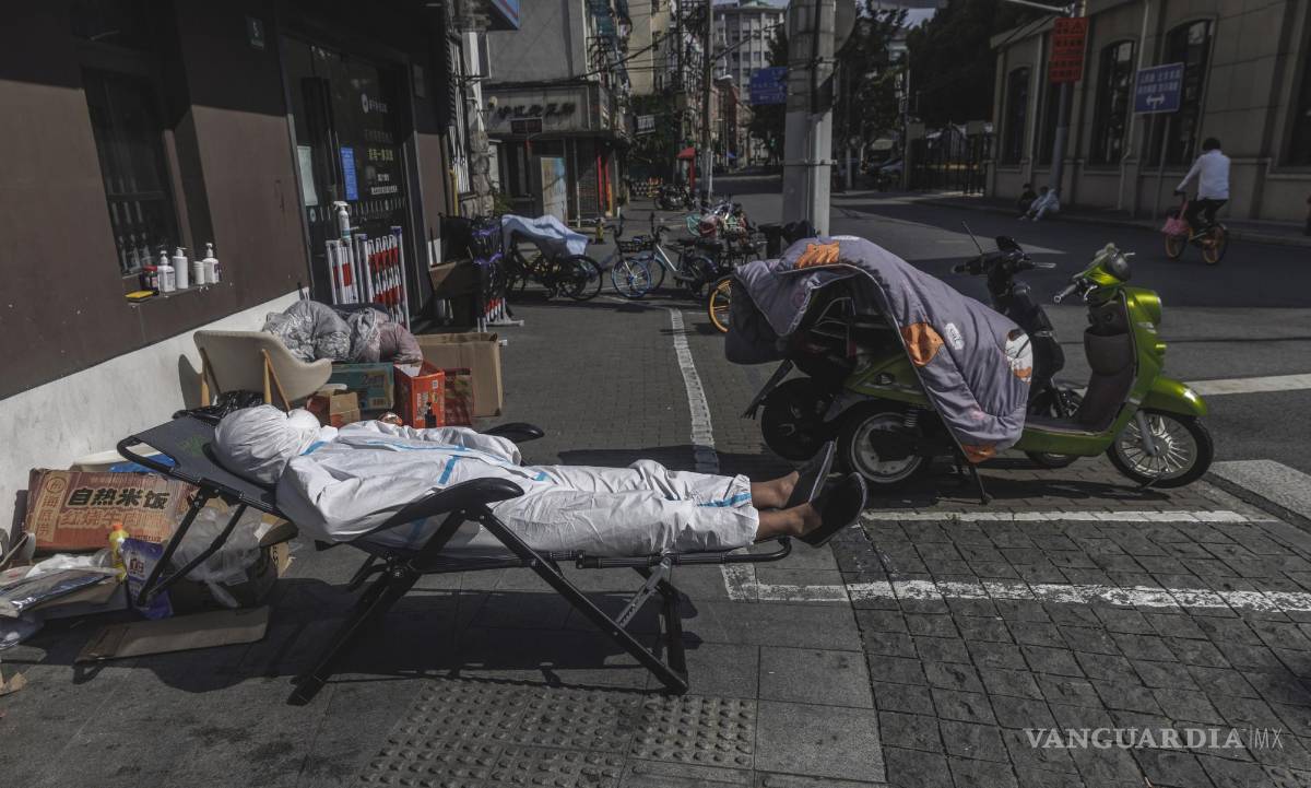 $!Un repartidor con equipo de protección duerme la siesta en la calle en medio del confinamiento por el COVID-19 en Shanghái, China.