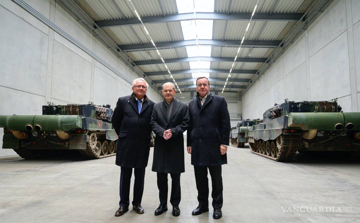 $!Armin Papperger director ejecutivo de Rheinmetall (i), el canciller alemán Olaf Scholz (c) en una sala con los principales tanques de batalla Leopard 2A4.