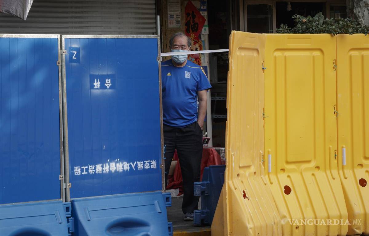 $!Un hombre se para detrás de las barreras de plástico antes de que se levante el cierre en Shanghái, China.
