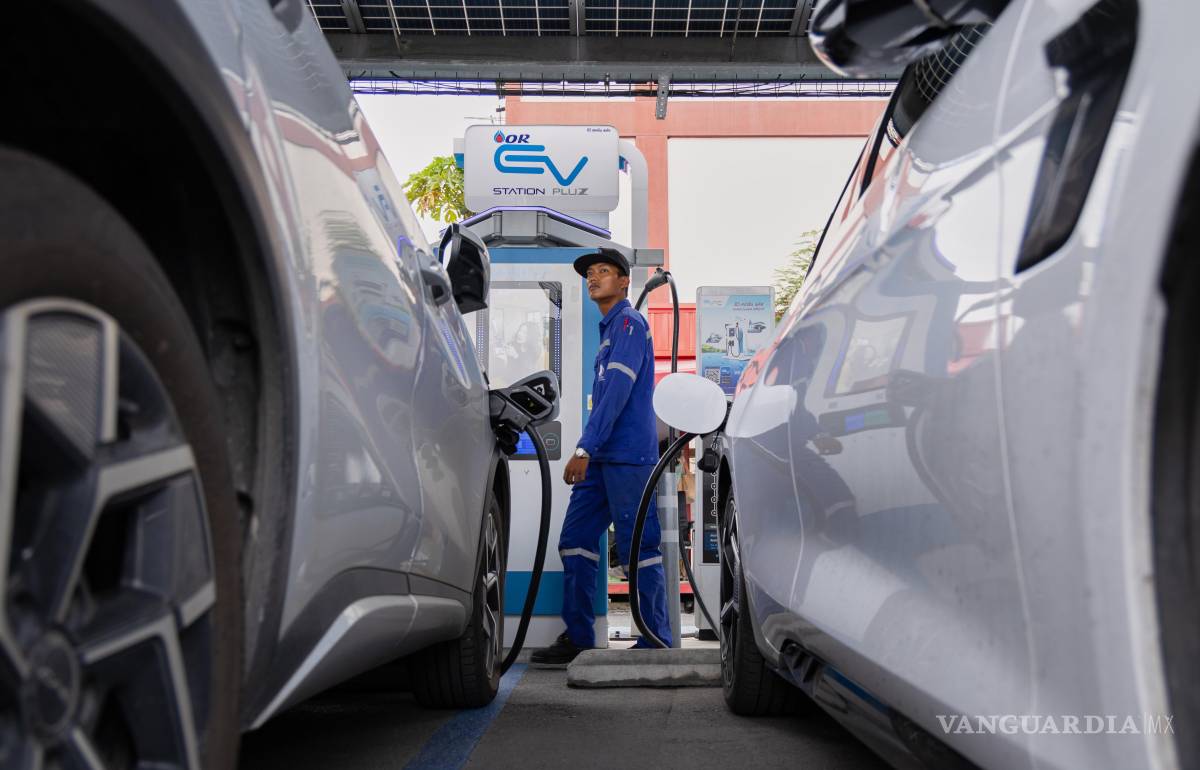 $!Khatawut Junsongsaeng, gerente de una estación de carga, pasa junto a dos vehículos eléctricos de fabricación china en un estacionamiento en Bangkok.
