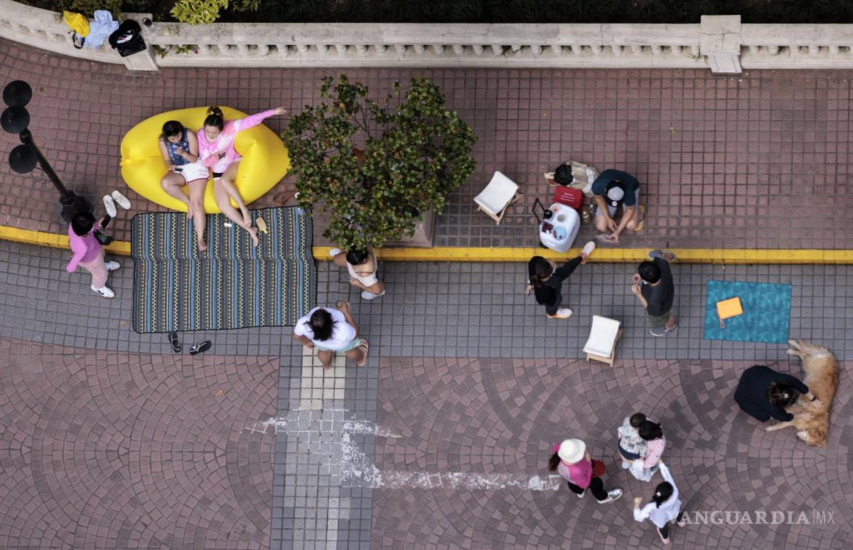 $!Las personas en cuarentena se reúnen fuera de su complejo residencial en Shanghái, China.