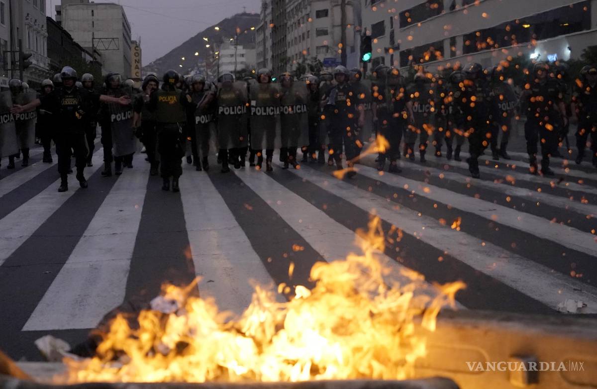$!La policía se acerca a la barricada en llamas levantada por los partidarios del derrocado presidente Pedro Castillo durante los enfrentamientos con la policía.