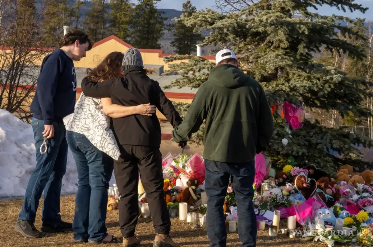 $!Residentes se abrazan mientras depositan flores en un monumento en memoria de las víctimas del tiroteo masivo en Tumbler Ridge, Columbia Británica, Canadá.