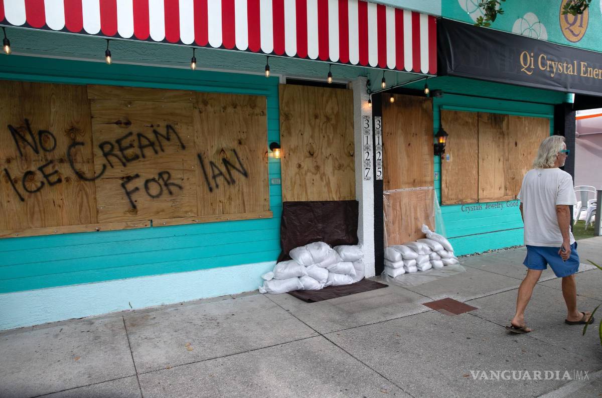 $!Una persona camina cerca de una heladería cubierta con madera contrachapada como preparación para el huracán Ian en Gulfport, Florida.