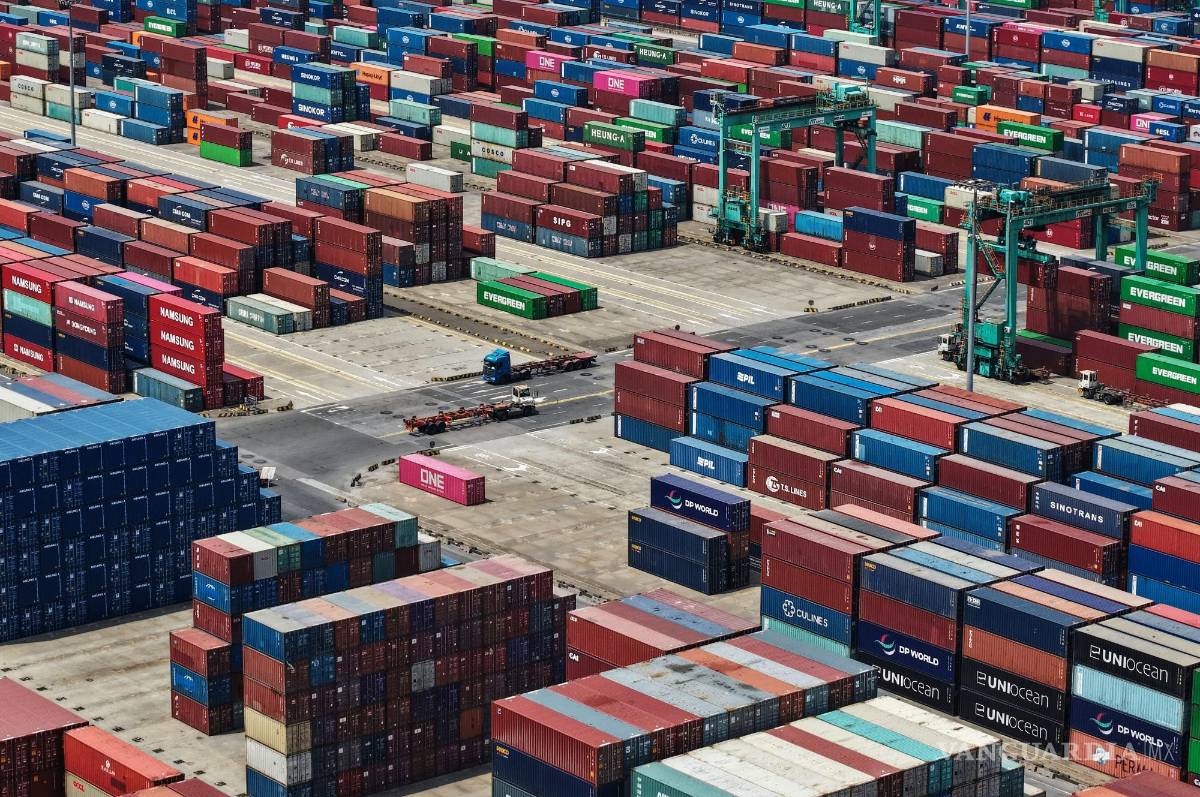 $!Camiones pasan junto a contenedores apilados en una terminal de contenedores en Shanghái. Las exportaciones chinas a países como Vietnam se han disparado.