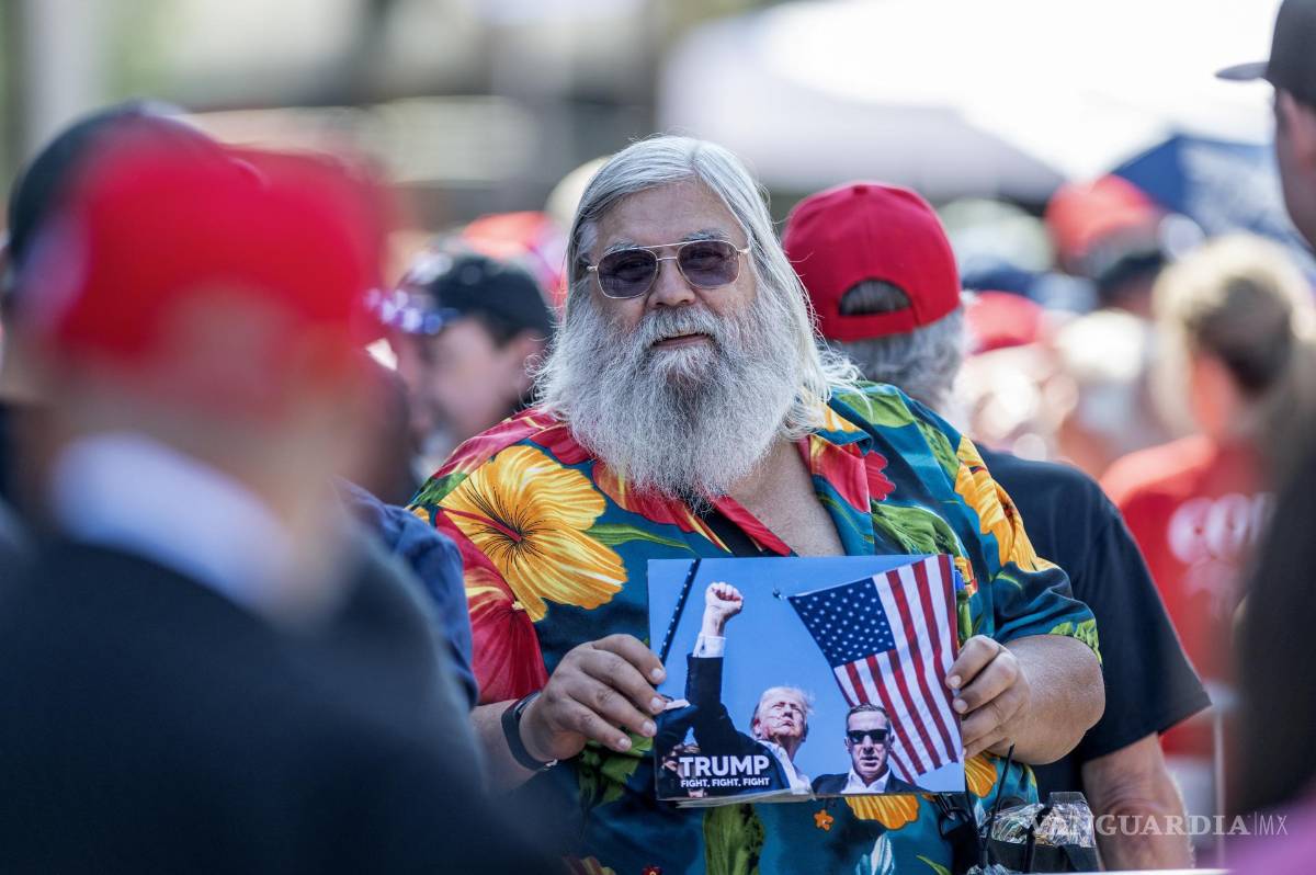 $!Un partidario sostiene una fotografía de Donald Trump mientras espera el inicio de un acto de campaña del candidato presidencial republicano en Asheville.