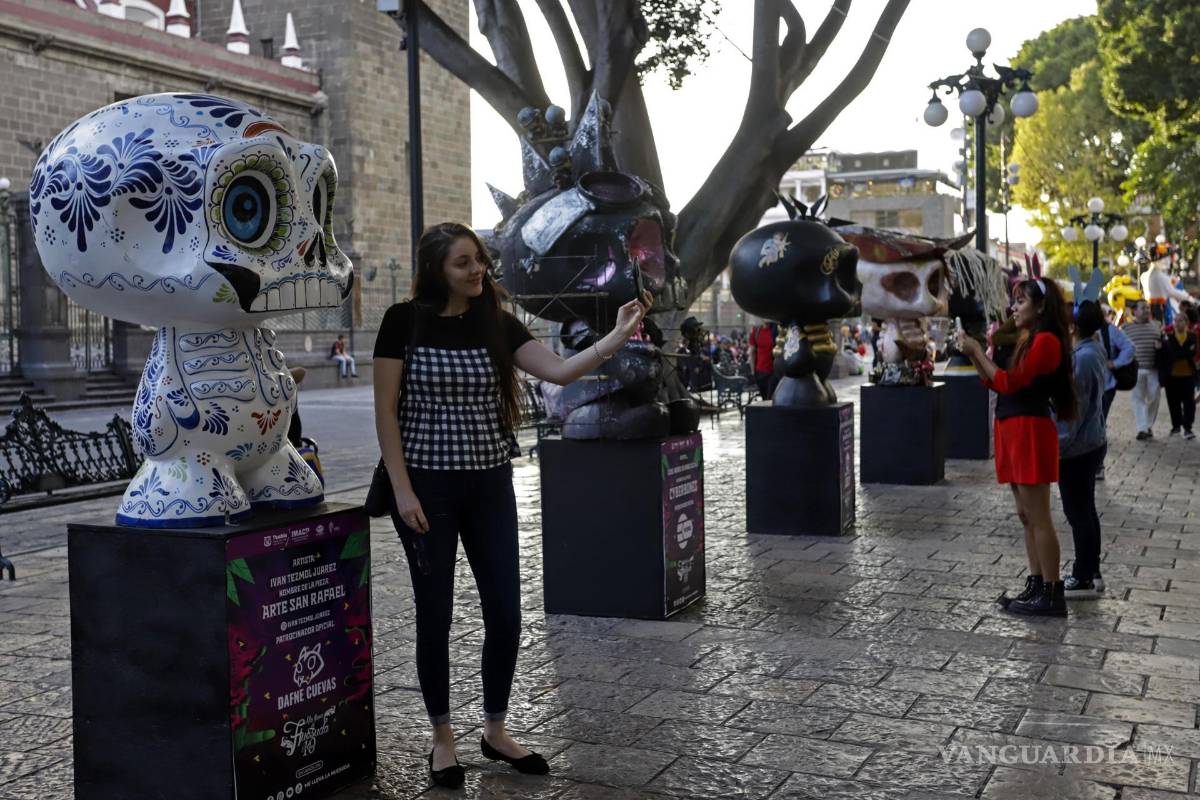 $!Personas admiran piezas de la exposición Me lleva la huesuda en el zócalo de la ciudad de Puebla (México).