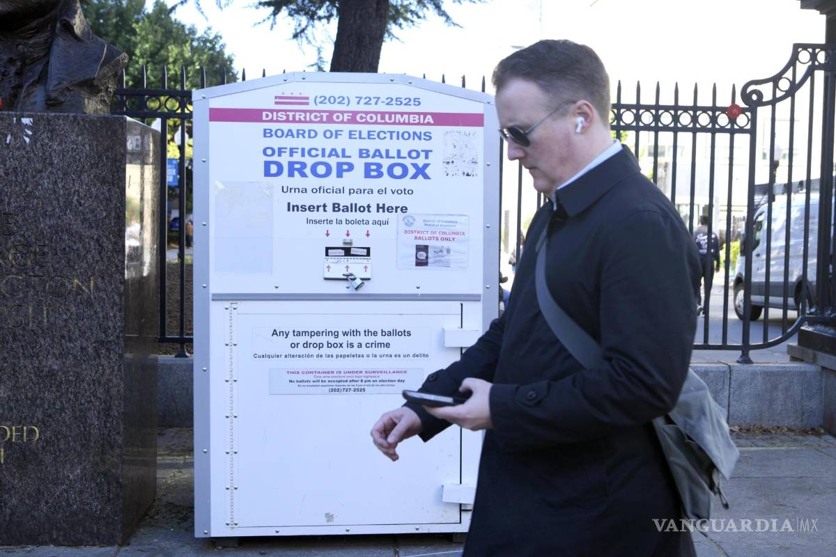 $!Un hombre caminan frente a una urna oficial de votación este martes, en una calle en Washington.