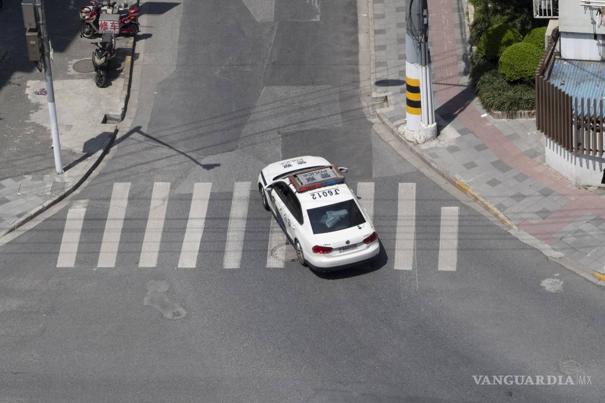 $!Un coche de policía patrulla una calle vacía en Shanghai, China.