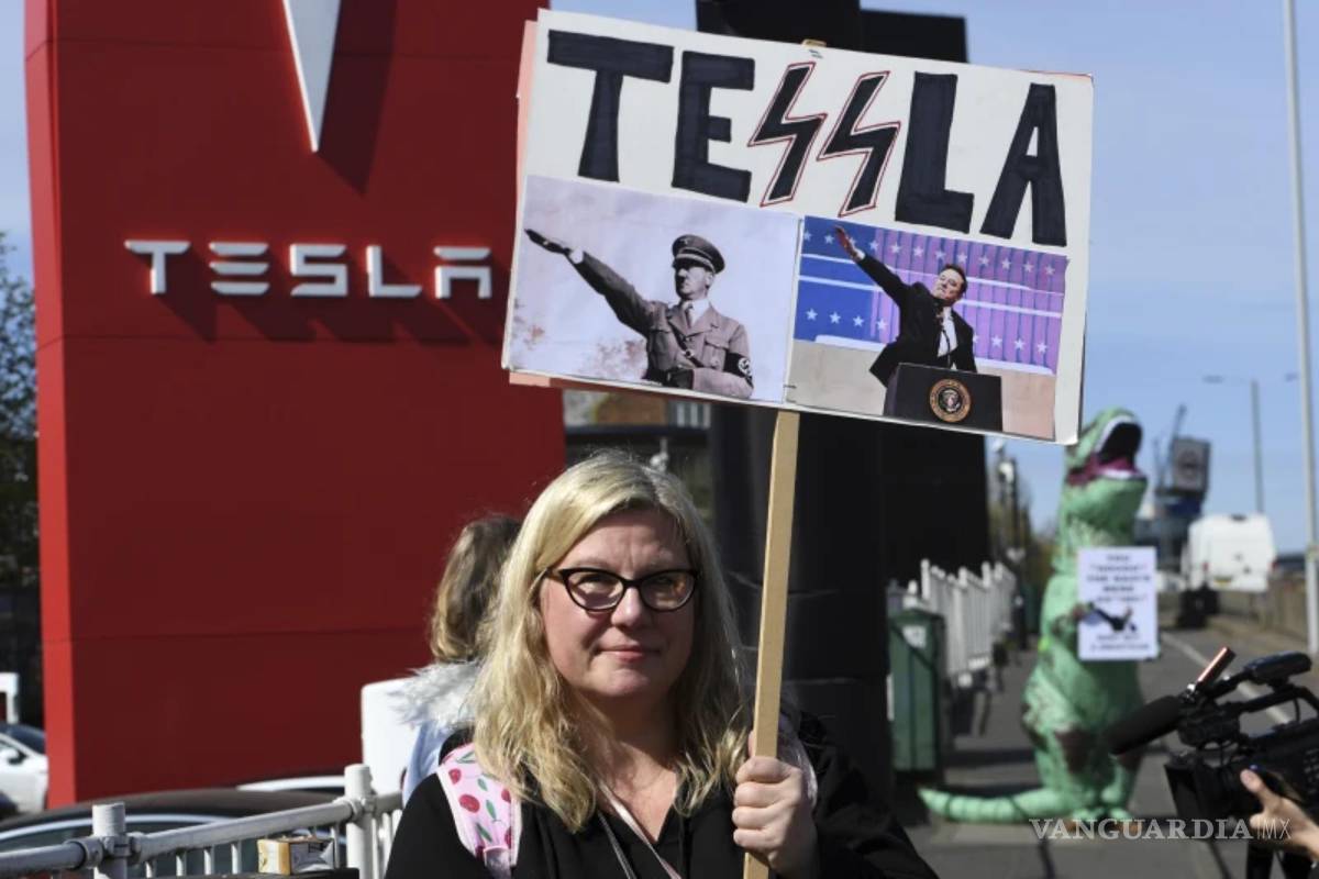$!Una manifestante sostiene una pancarta mientras participa en el Día de Acción Global para Derribar Tesla cerca de un concesionario de Tesla en Londres.