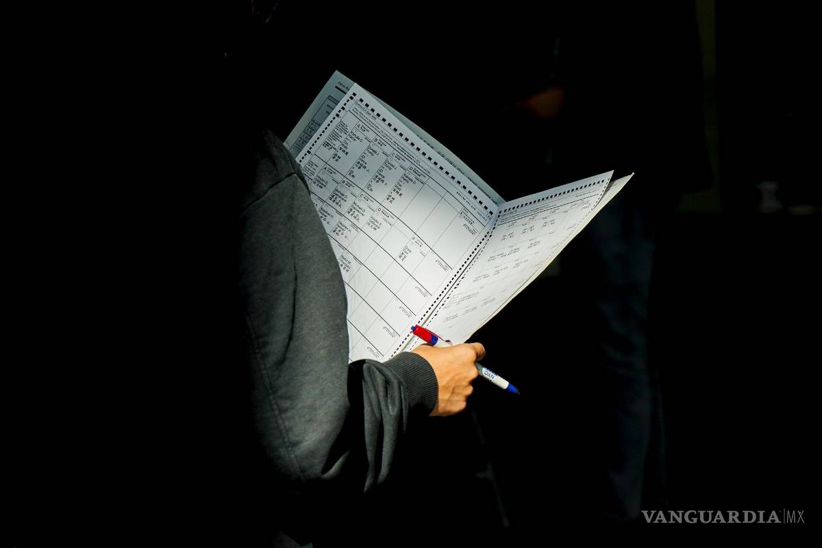 $!Una mujer mira su papeleta mientras hace cola para la votación anticipada en un centro de votación en Queens.