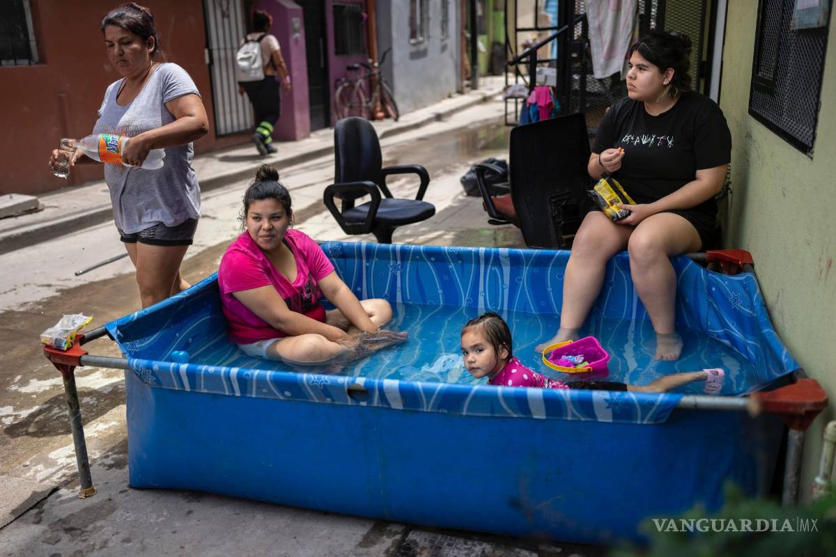 $!Miembros de la familia Sánchez se refrescan en una piscina de plástico fuera de su casa en el barrio Padre Carlos Múgica de Buenos Aires, Argentina.