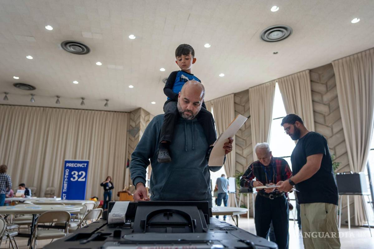 $!Three-year-old Zayn, sits on his father's shoulders as he inserts his ballot into a machine to vote at the First Presbyterian Church of Dearborn, on Election Day, Tuesday, Nov. 5, 2024, in Dearborn, Mich. (AP Photo/David Goldman)